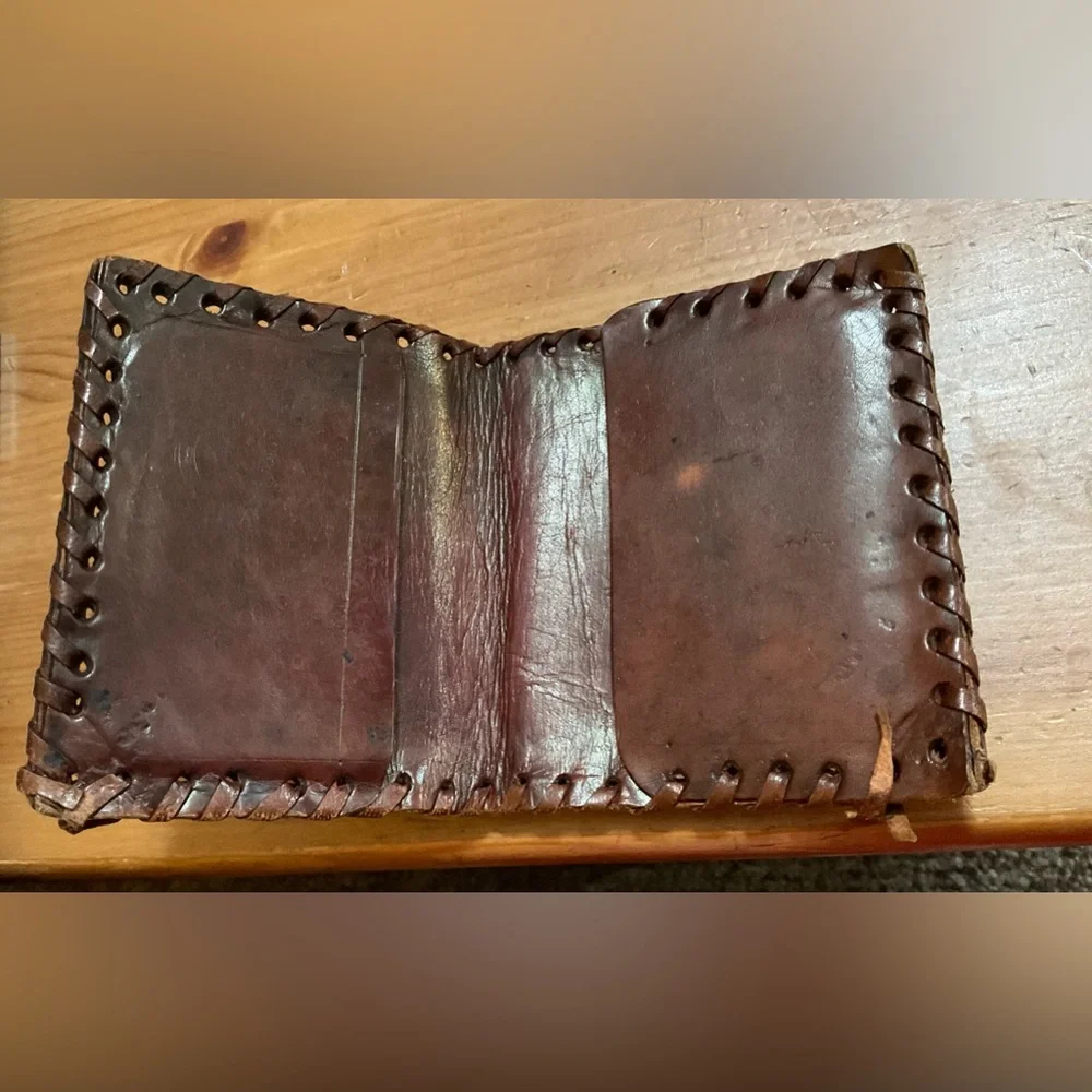Hand crafted tooled mens leather design bifold wallet laced stitching around it.